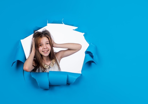 Niña niño toque el cabello en el espacio de copia de fondo azul para el anuncio