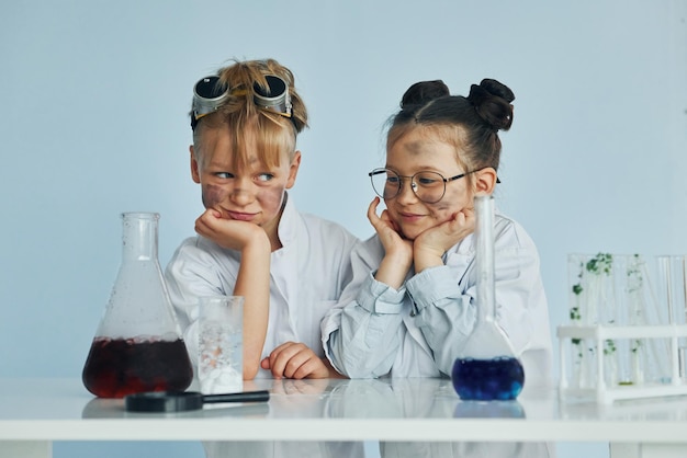 Niña con niño trabajando juntos Los niños con batas blancas juegan a los científicos en el laboratorio usando equipo