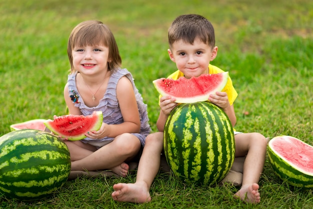 Foto niña y niño con un trozo de sandía en las manos