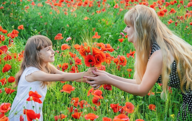 Niña de los niños en un campo con amapolas. enfoque selectivo