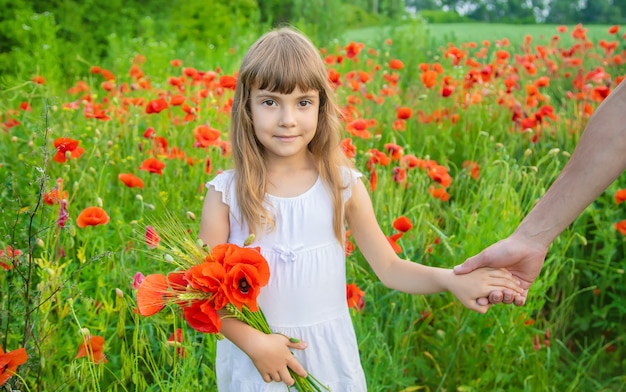 Niña de los niños en un campo con amapolas.