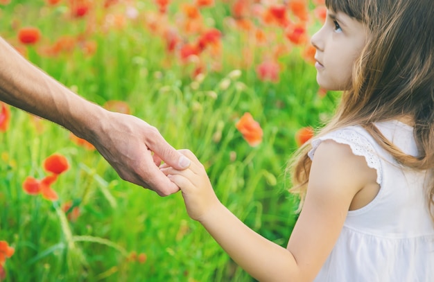 Niña de los niños en un campo con amapolas.