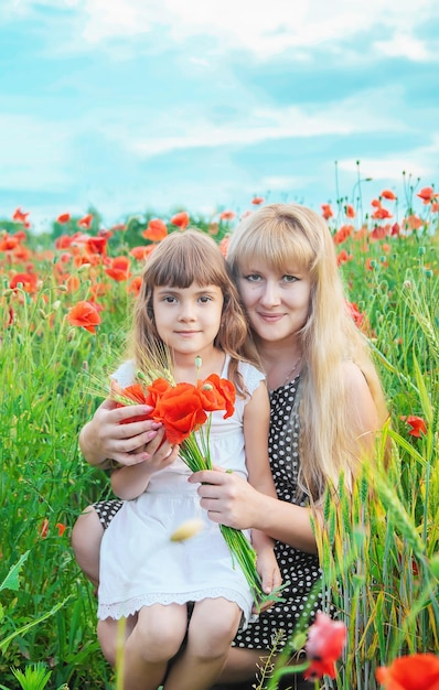 Niña de los niños en un campo con enfoque selectivo de amapolas