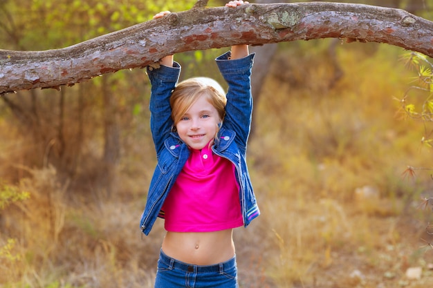 niña niños columpiándose en un tronco en un bosque de pinos