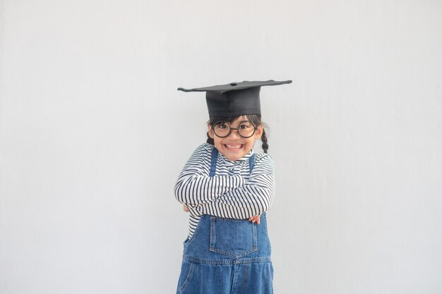 Foto niña de niños con una gorra de posgrado sobre fondo blanco muy feliz y emocionado