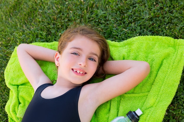 niña de los niños relajado tumbado en una toalla sobre la hierba verde