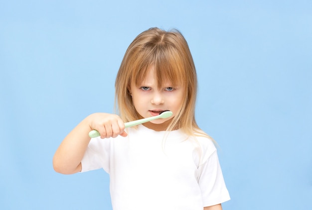 Niña no quiere cepillarse los dientes. Niña triste con cepillo de dientes