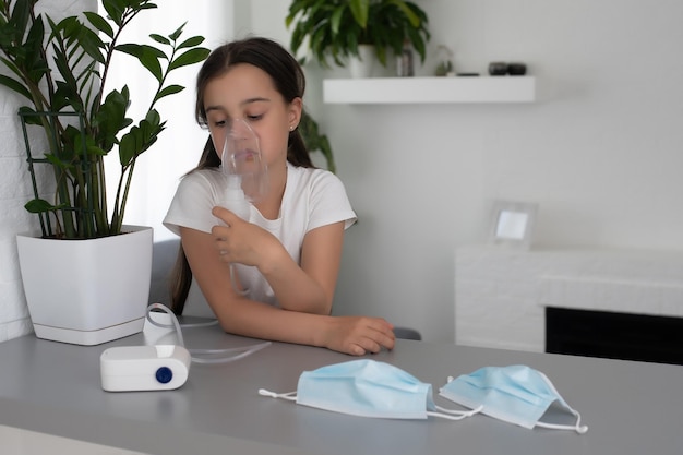 Niña de nueve años con asma alérgica, inhalando su medicamento a través del espaciador mientras mira con ojos cansados.