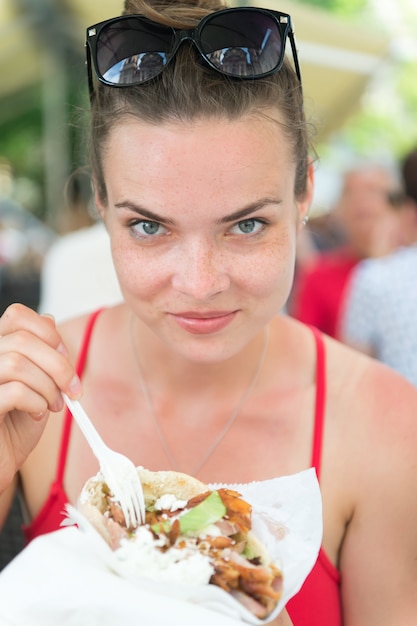 Foto niña o mujer comiendo giroscopios sándwich. chica con placer come hamburguesa después de dieta.