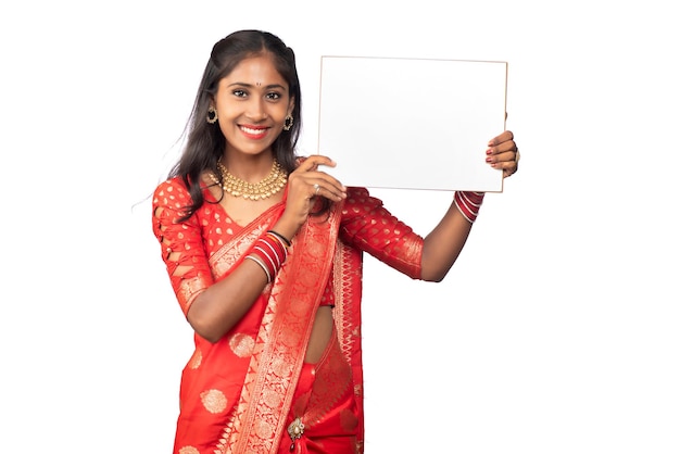 Una niña o mujer de negocios con un sari y sosteniendo un letrero en sus manos sobre un fondo blanco.
