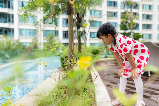 Niña, observa la planta en el jardín.