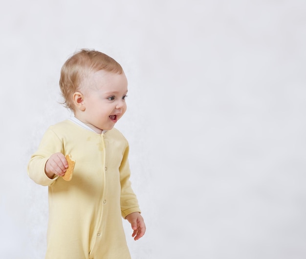 Una niña de ocho meses vestida con un pijama amarillo juega en su habitación