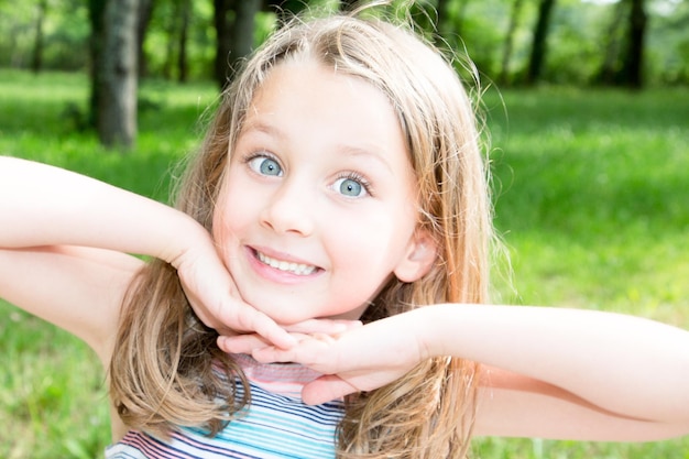 Niña con ojos azules profundos en un parque verde y soleado