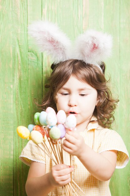 Niña con orejas de conejo y huevos pequeños. Celebración de pascua