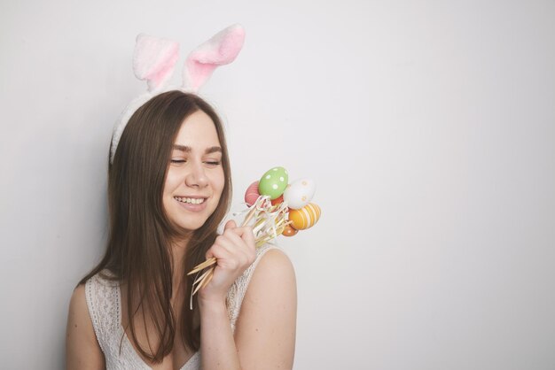 Una niña con orejas de conejo en las manos sostiene huevos de pascua sobre un fondo blanco el concepto de pascua