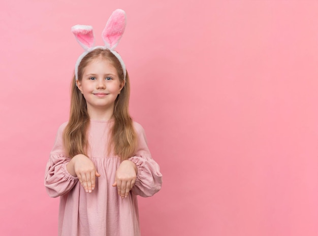 Niña con orejas de conejo sobre fondo rosa con espacio de copia Niña de Pascua sobre fondo rosa