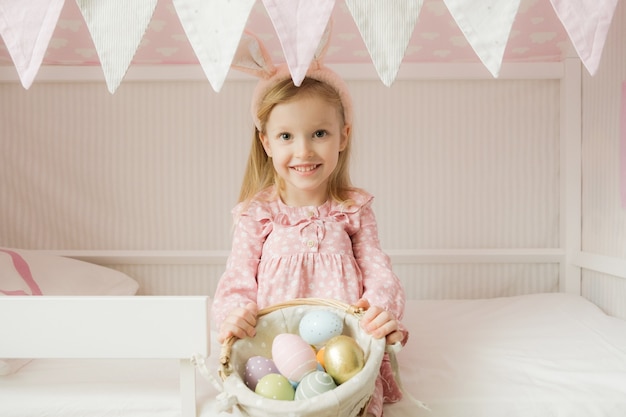 niña con orejas de conejo y sosteniendo una canasta de huevos de Pascua