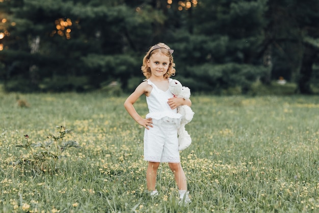 Una niña con un oso blanco en la mina al aire libre al atardecer.