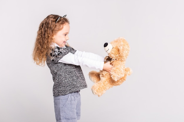 Foto niña con oso de pie en blanco