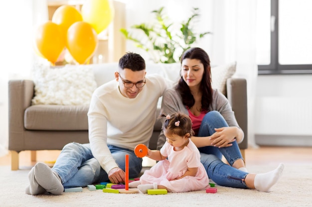 niña con padres jugando con juguete de pirámide