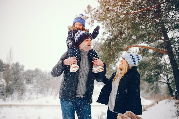 Niña con padres jugando en un parque de invierno