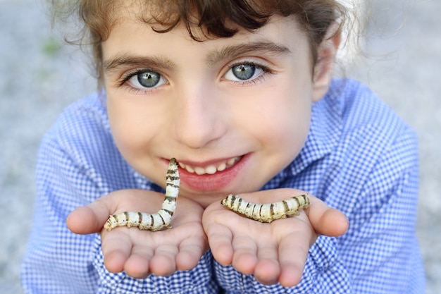 Niña palying con gusano de seda en las manos