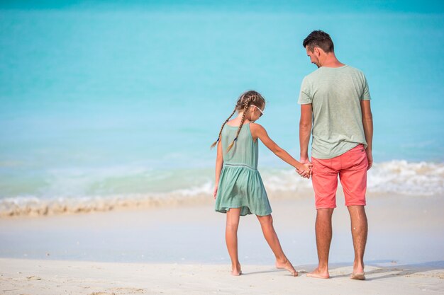 Niña y papá feliz divirtiéndose durante las vacaciones en la playa