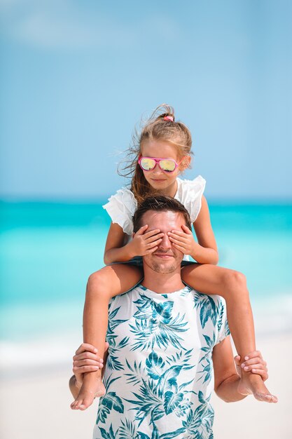 Foto niña y papá feliz divirtiéndose durante vacaciones en la playa