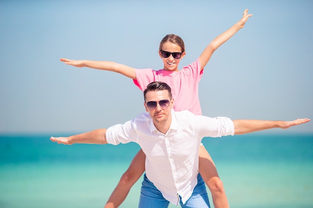 Niña y papá feliz divirtiéndose durante vacaciones en la playa