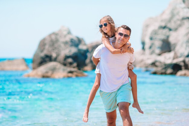 Niña y papá feliz divirtiéndose durante vacaciones en la playa