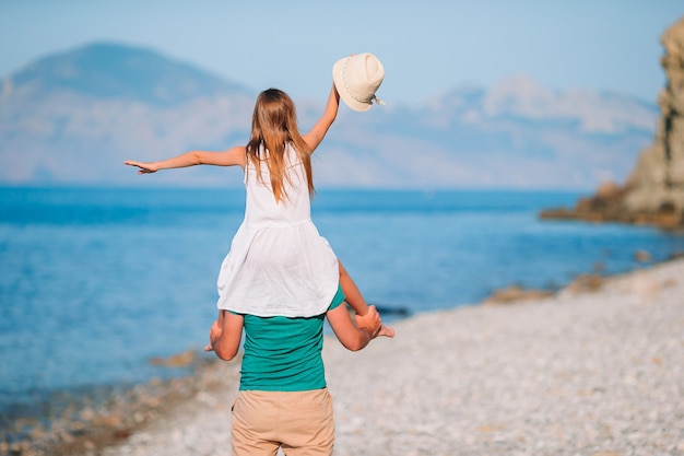 Niña y papá feliz divirtiéndose durante las vacaciones en la playa