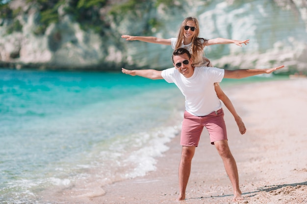 Niña y papá feliz divirtiéndose durante las vacaciones en la playa