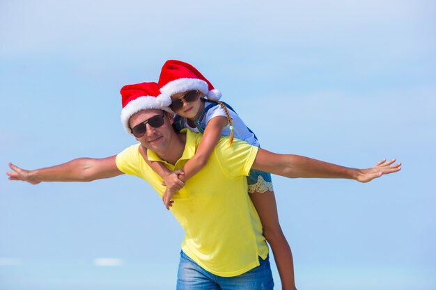 Niña y papá feliz en Santa Hat durante vacaciones en la playa