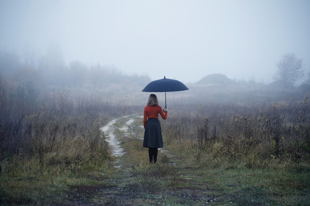 Foto niña con paraguas en campo de otoño