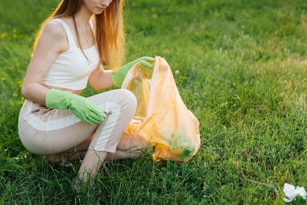 Una niña en el parque al atardecer se dedica a la recolección de basura en el parque Reciclaje de residuos de cuidado ambiental Clasificación de basura