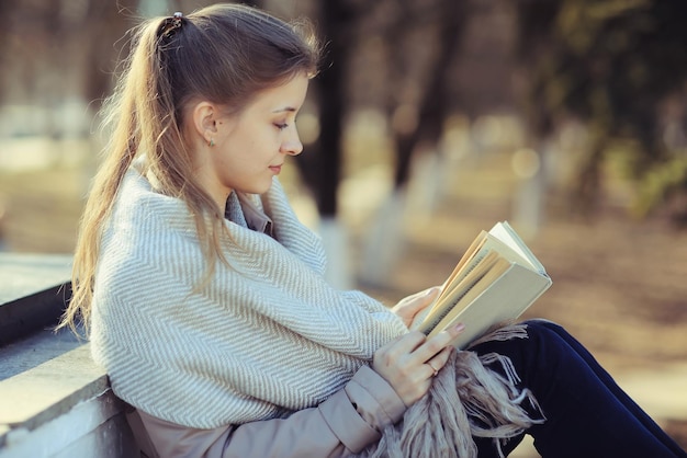 niña en el parque de otoño con un libro