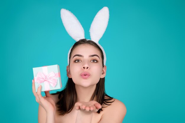 Niña de Pascua joven con orejas de conejo de Pascua sosteniendo huevos de colores decorativos en el fondo del estudio