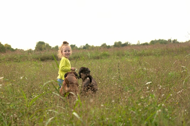 niña en un paseo por el parque con dos perros grandes