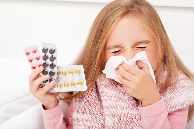 Una niña con pastillas en sus manos.