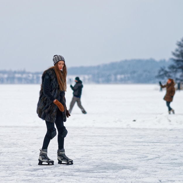 Niña patinando sobre hielo en la pista de invierno cubierta de nieve en Trakai, Lituania.