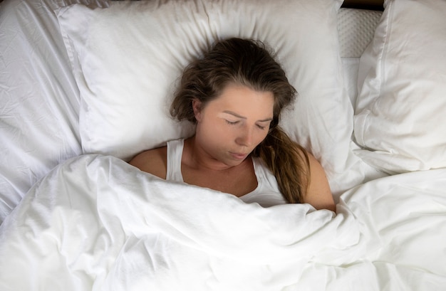 Foto niña con pecas durmiendo con sábanas blancas vista superior retrato de la hermosa joven