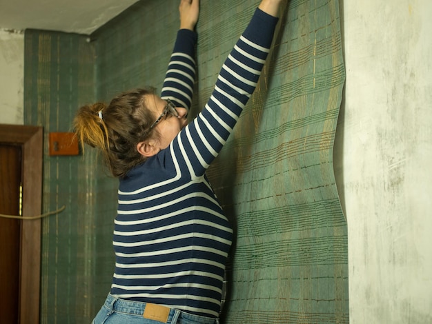 Niña pegando papel tapiz en el pasillo renovación de apartamento