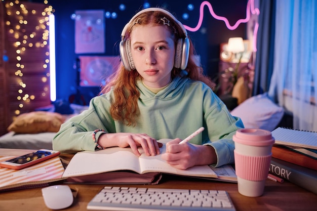 Niña pelirroja haciendo la tarea por la noche