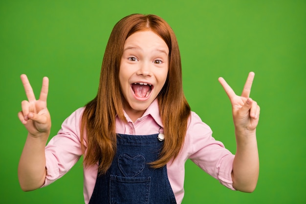 Foto niña pelirroja posando contra la pared verde