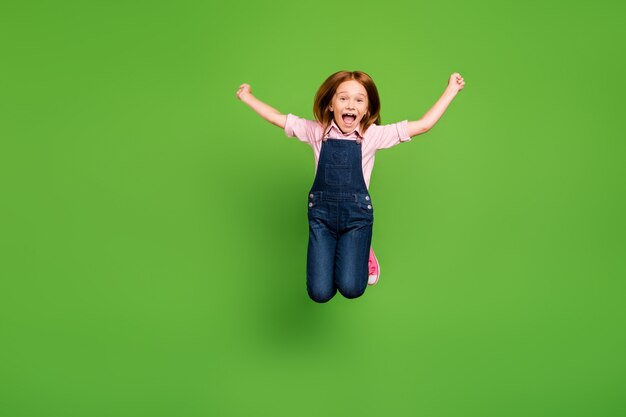 Niña pelirroja posando contra la pared verde