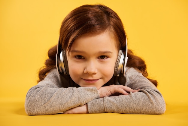 Niña pelirroja con la reclinación de los auriculares.