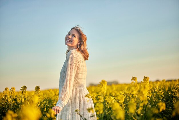 Foto niña pelirroja con vestido blanco en el campo de rap