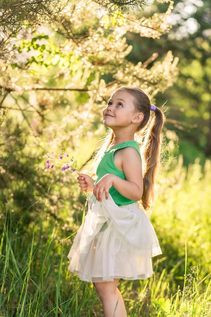 Niña con el pelo largo con un vestido sobre la naturaleza en verano