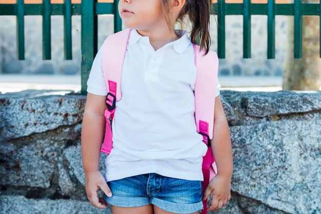 Foto una niña de pelo negro se sienta cerca de una valla.