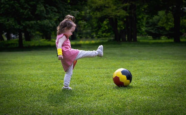 Una niña con una pelota de fútbol en el césped